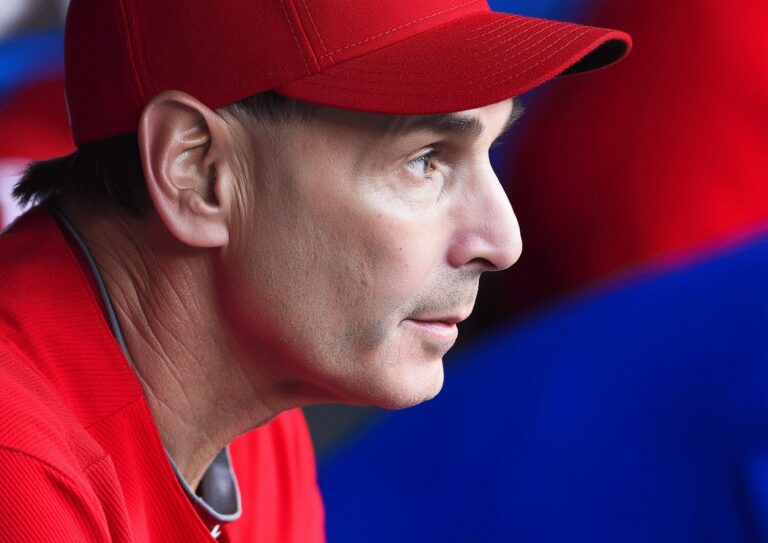 Focused senior coach in a red cap and shirt, attentively observing during a training session.